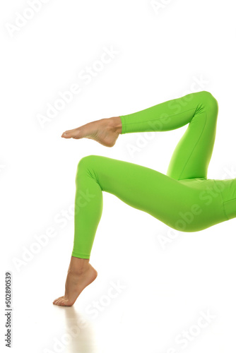 Sporty green leggings on slim pretty bare legs on a white background. Side view