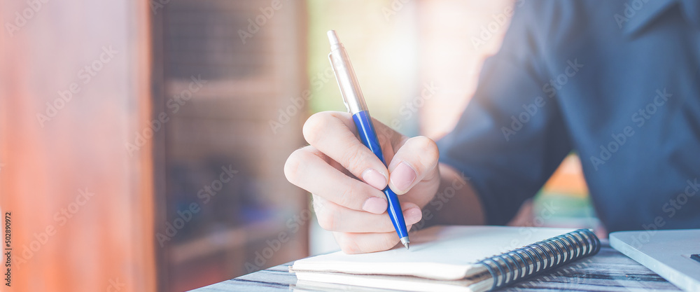 Woman hand writing on a notepad with a pen in the office.