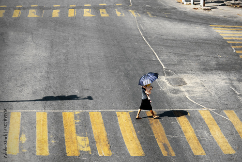 Woman holding daugther with umbrella  crossing the street at crossroads