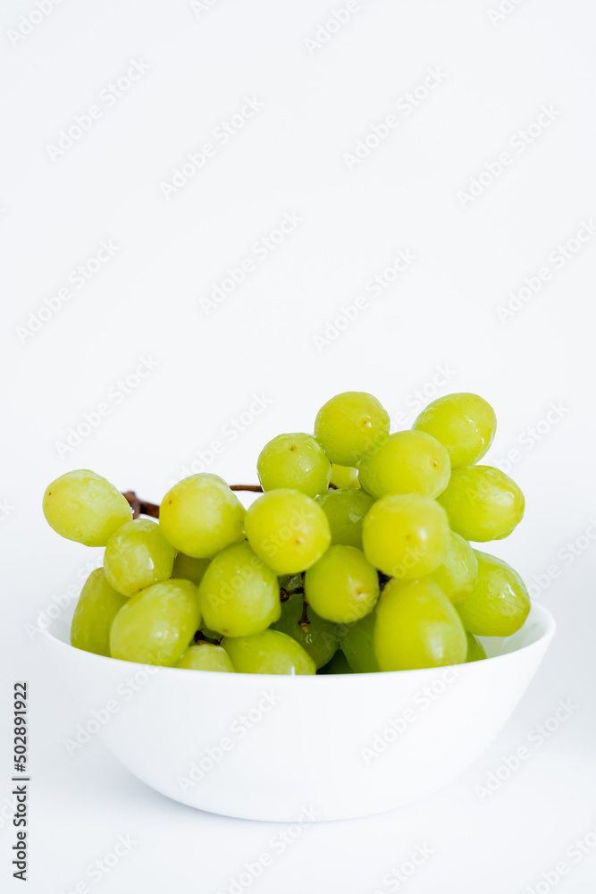 sweet green grapes in bowl on white.