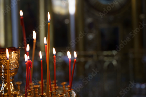 Candles in a Christian Orthodox church background. Flame of candles in the dark sacred interior of the temple