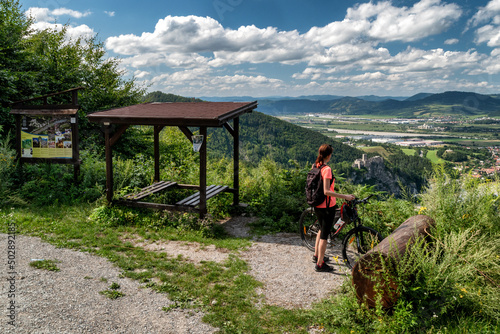 Woman cyclist standing near bike and looking on beautiful Slovak nature photo