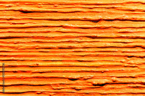 Lot of parallel thick strokes of orange paint on canvas. Abstract texture with line structure