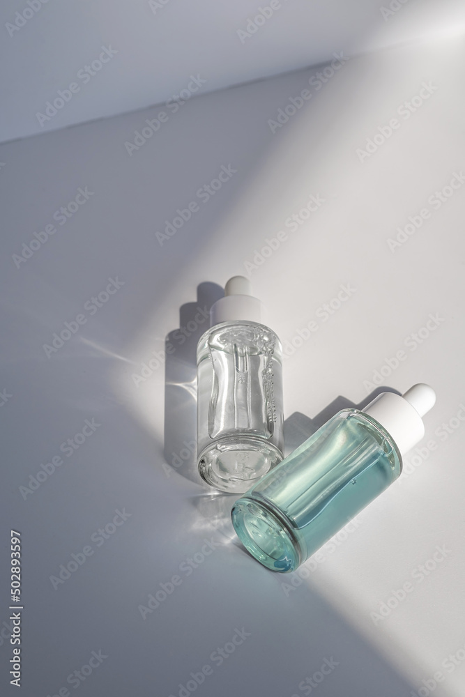 Two laconic bottles of cosmetic liquid in the rays of the harsh sun. Two laconic bottles of cosmetic liquid in the rays of the harsh sun.