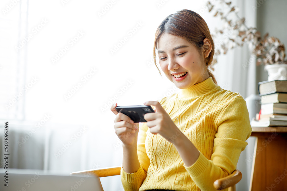 Asian young woman happiness and enjoy play game application from mobile phone connect internet with copy space Asian young woman happiness and enjoy play game application from mobile phone connect internet with copy space