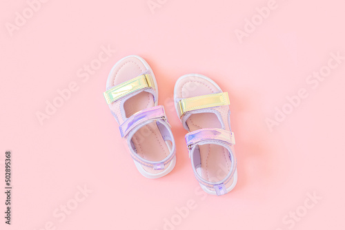 Stylish holographic sandals for kids on pink background. Shiny fashion summer shoes. Flat lay, Top view