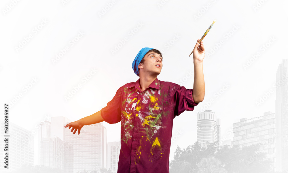 Young emotional artist gesturing with paintbrush Young emotional artist gesturing with paintbrush