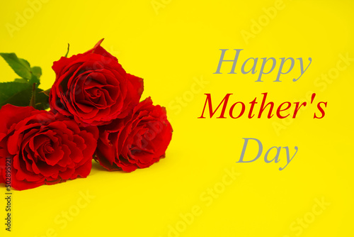 Red roses for mom on a yellow background, text HAPPY MOTHER'S DAY, in gray and red. The concept of a gift, congratulation, gratitude, postcard, surprise. High quality photo