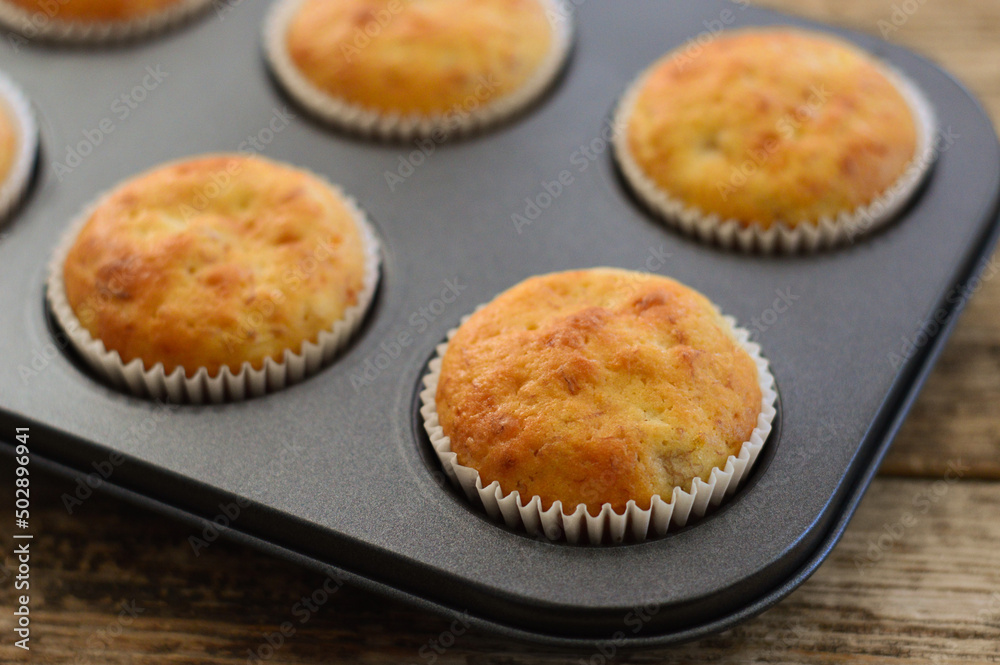 Homemade muffins. Muffins in baking molds. Muffins on a wooden background.