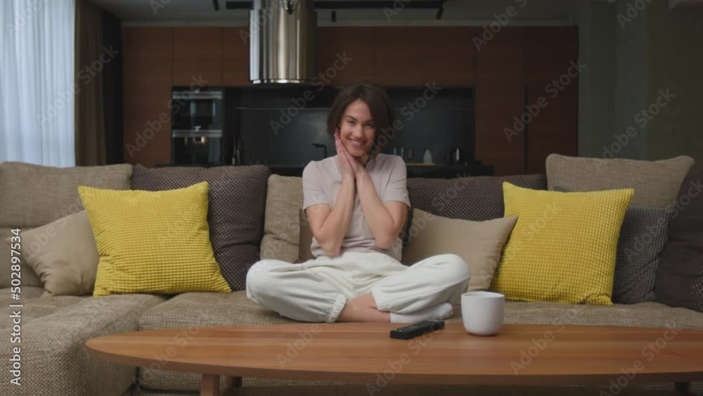 Touched young girl smiling watching series, feel happy from tender moment of romantic movie, sitting on cozy couch Touched young girl smiling watching series, feel happy from tender moment of romantic movie, sitting on cozy couch