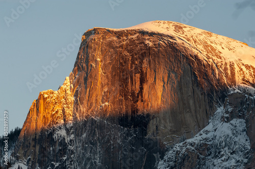 The last light of the setting sun illuminating a snow-covered half-dome on a winter afternoon. Yosemite national park. photo