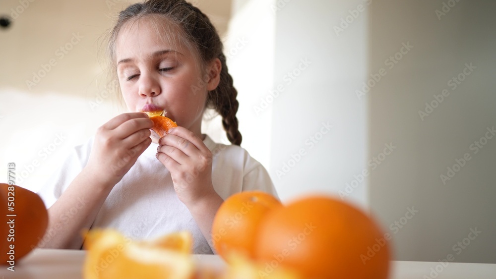 girl child eating oranges. happy family fruit healthy food dream kid concept. little girl daughter eating oranges at the table in the kitchen indoors. juicy fruits oranges are for a healthy diet girl child eating oranges. happy family fruit healthy food dream kid concept. little girl daughter eating oranges at the table in the kitchen indoors. juicy fruits oranges are for a healthy diet