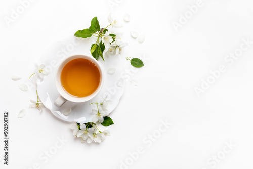 Spring image. Top view cup of green tea on figured saucer with white apple tree flowers on white.
