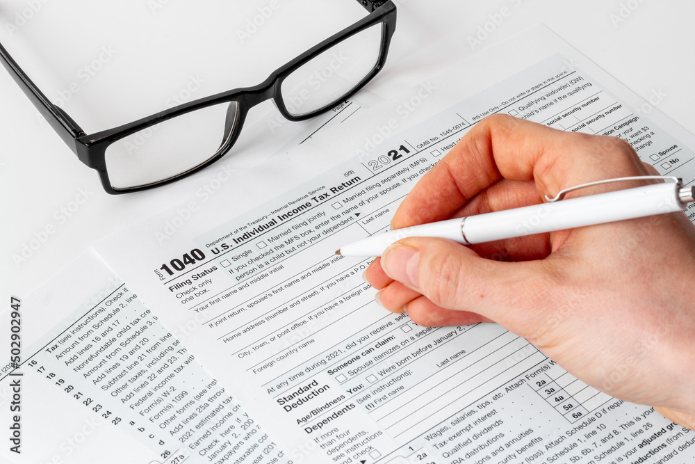 Hands filling US tax form. Culculating and payment of taxes concept Hands filling US tax form. Culculating and payment of taxes concept