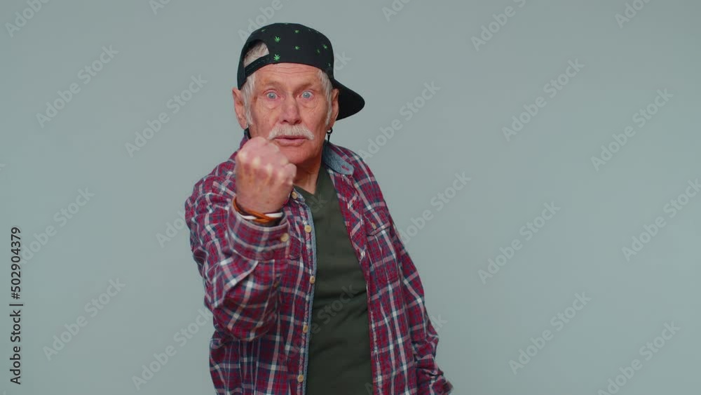 Aggressive angry senior man 80s in shirt trying to fight at camera, shaking fist, boxing with expression, punishment, disappointment. Elderly grandfather isolated alone on gray studio wall background Aggressive angry senior man 80s in shirt trying to fight at camera, shaking fist, boxing with expression, punishment, disappointment. Elderly grandfather isolated alone on gray studio wall background