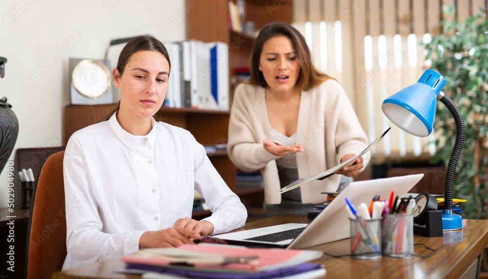 Obraz premium Outraged business woman expressing dissatisfaction with work of confused secretary in office