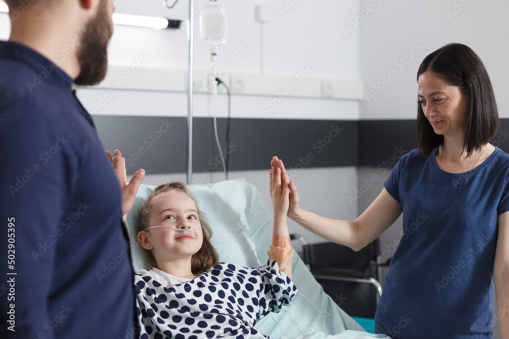 Obraz premium Happymother and father congratulating ill little daughter for successful treatment and recovery results. Peaceful relaxed parents congratulating sick child for amazing health results