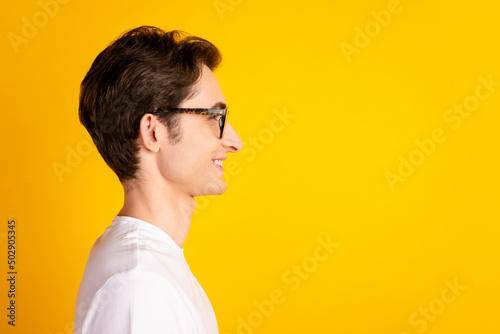 Profile side photo of young cheerful guy look empty space smart eyewear isolated over yellow color background