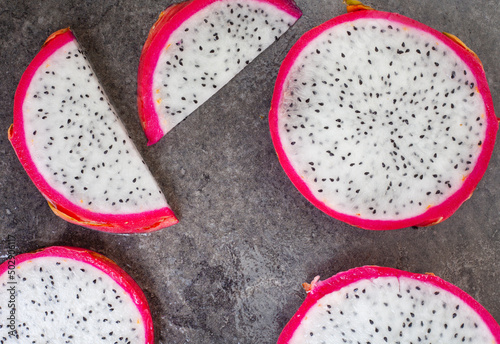 Dragon fruit slices on grey mottled surface and ample copy space