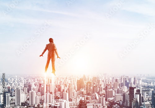 Fotografering Businessman in suit and aviator hat flying in sky