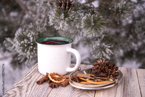 Close-up of a ceramic white mug with mulled wine and spices on a wooden table in winter.