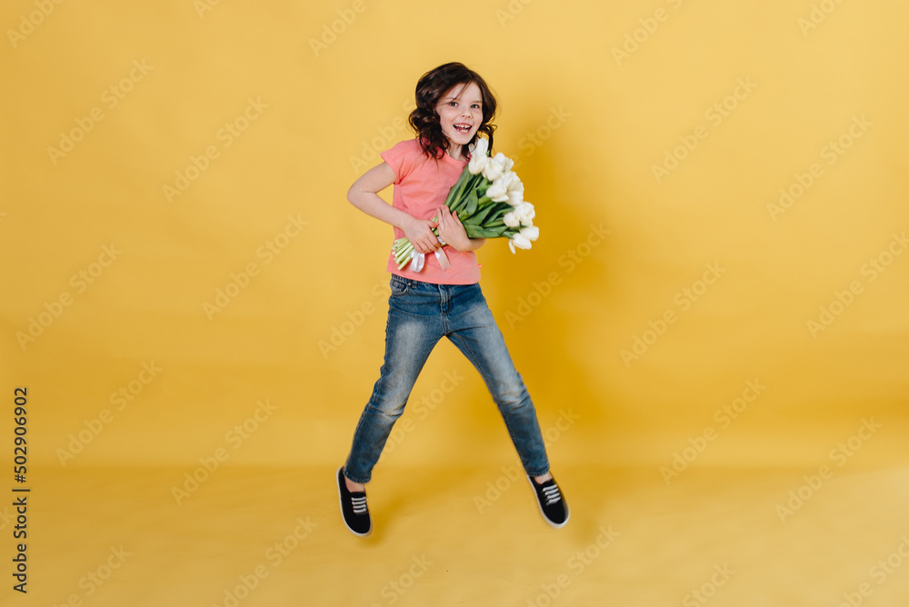 Photo of a cute girl on a yellow background holding a bouquet of white tulips as a gift that she will give to her mother
Photo of a cute girl on a yellow background holding a bouquet of white tulips as a gift that she will give to her mother