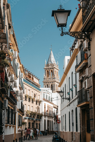 Sunny street in Triana district in Seville, in background bell tower of church photo