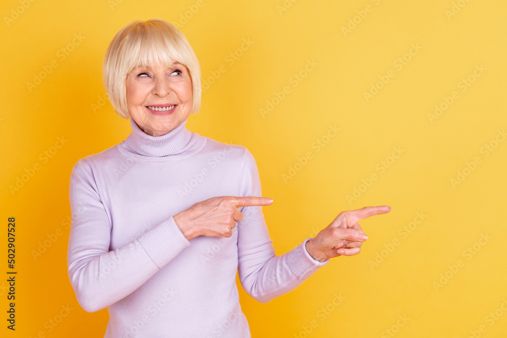 Photo of mature lady point fingers empty space promotion proposition isolated over yellow color background Photo of mature lady point fingers empty space promotion proposition isolated over yellow color background