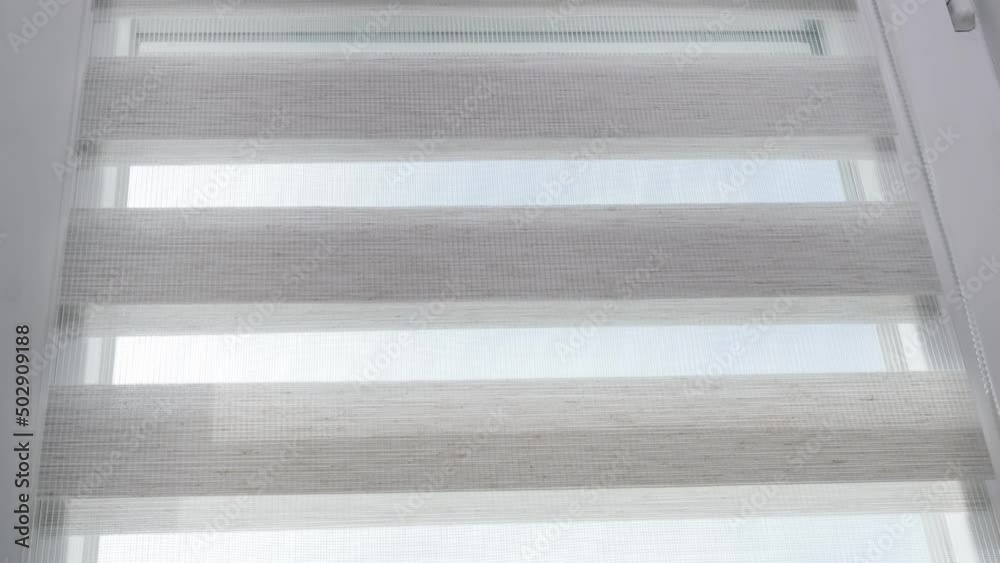 The mechanism of tnaninny roller blinds close up. Duo window roller system day and night. Close up on roller blinds indoors. The mechanism of tnaninny roller blinds close up. Duo window roller system day and night. Close up on roller blinds indoors.