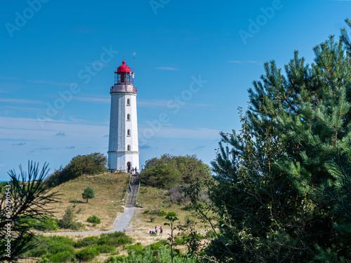 The Hiddensee Light House with the name Dornbusch is surrounded from green nature and blue sky background 