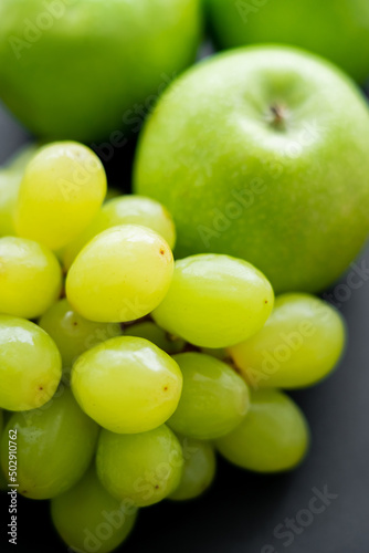 close up view of tasty apples and green grapes on black.