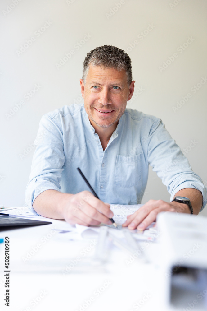 Business portrait of architect sitting at his work table and planning in his modern bright office Business portrait of architect sitting at his work table and planning in his modern bright office