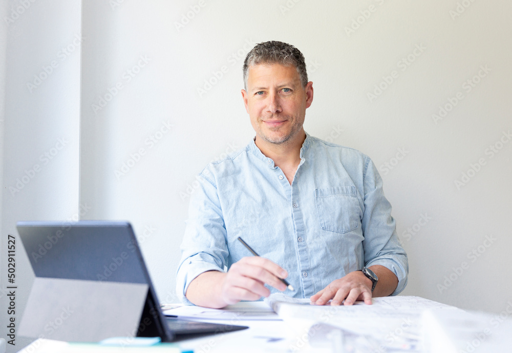 Business portrait of architect sitting at his work table and planning in his modern bright office Business portrait of architect sitting at his work table and planning in his modern bright office
