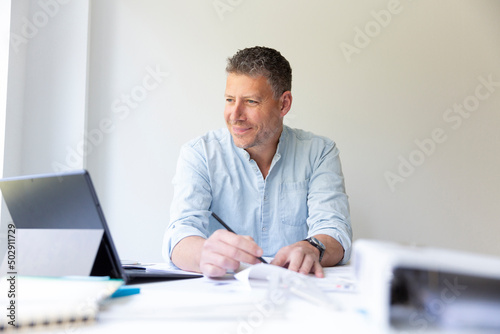 Business portrait of architect sitting at his work table and planning in his modern bright office
