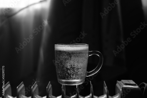 A cup of draft beer stands on an electric heater