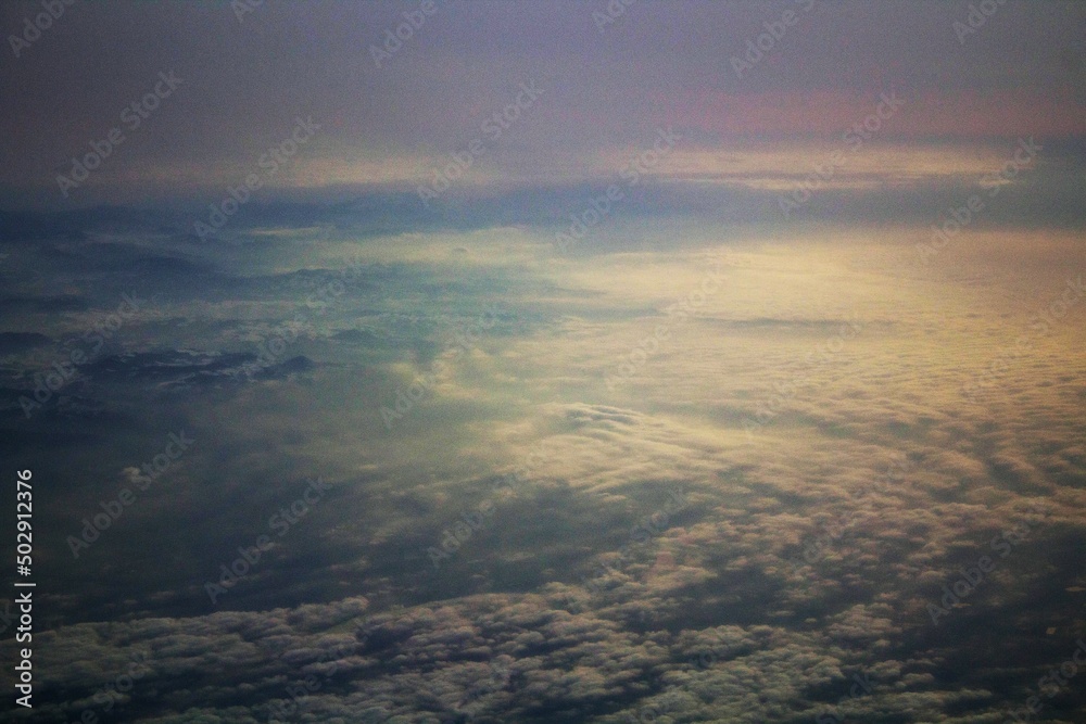 spectacular sunset seen from an airplane with clouds in the foreground and in the distance
