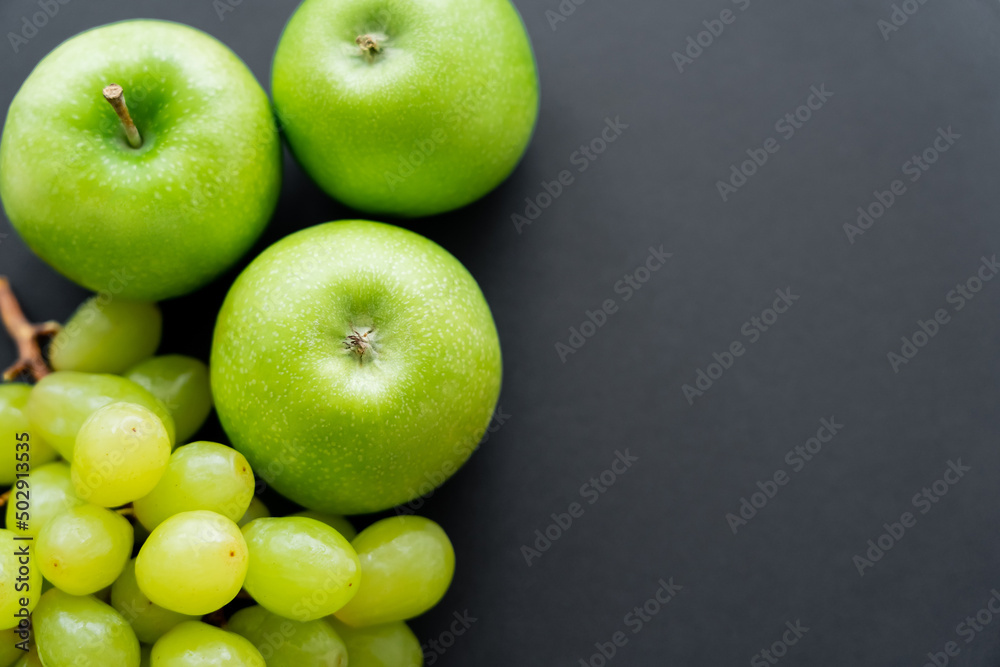 top view of tasty apples and green grapes on black. top view of tasty apples and green grapes on black.