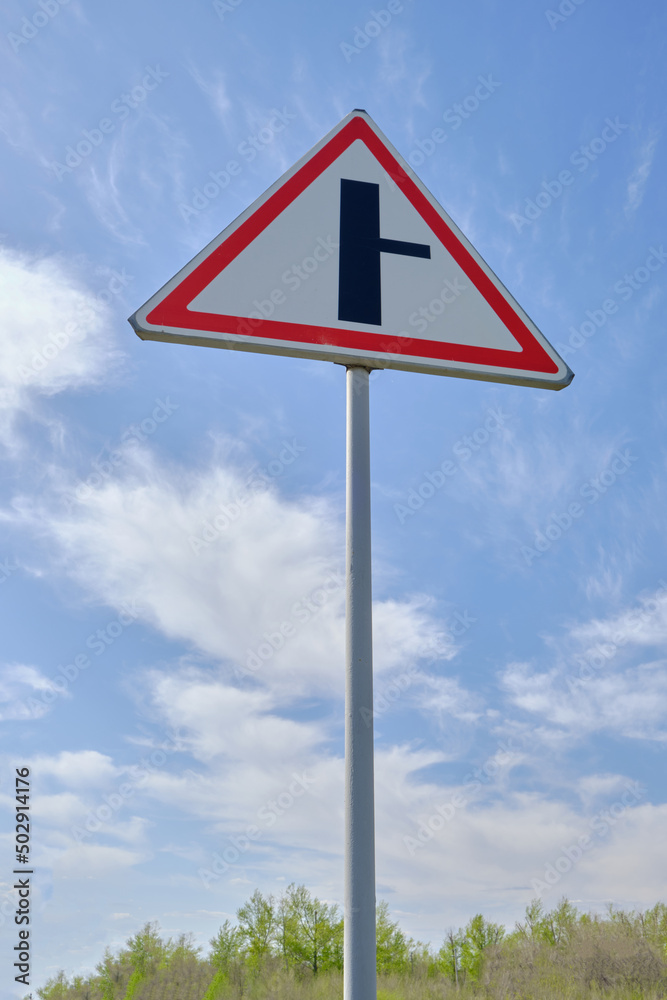 Road sign warning turn from main road blue sky background.