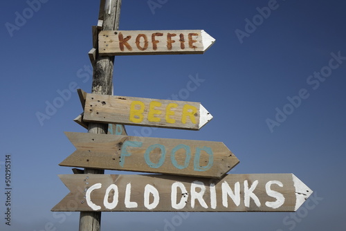 Colourful, handmade wooden signpost for food and beverages ('Koffie': coffee) under blue sky, concept: leisure, holiday, enjoyment (horizontal), Noordwijk, South Holland, Netherlands
