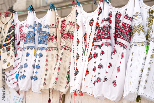 Variety of ethnic ukrainian traditional embroidered shirts, vyshyvanka - traditional embroidered clothes on flea market or national festival. Vintage goods on flea market. Symbol of Ukrainian culture © Iryna Mylinska