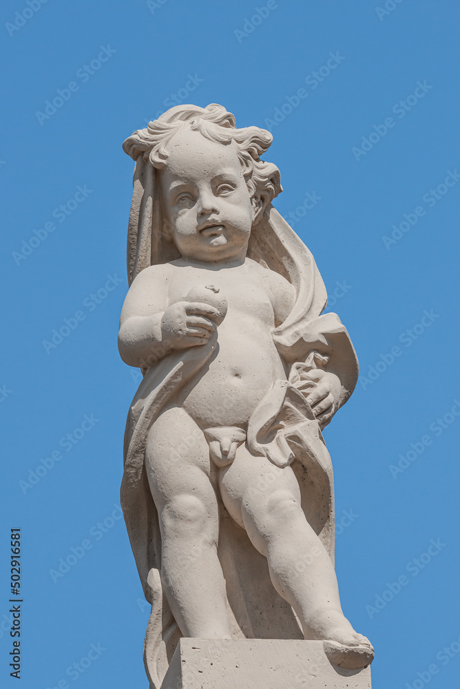Old statue of a small child in the historical downtown of Dresden, Germany, at blue sky background.
