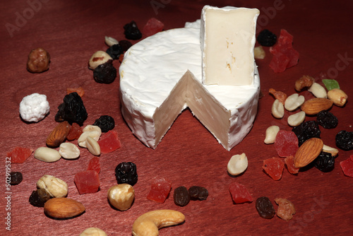 sliced brie cheese with nuts and dried fruits on a wooden table