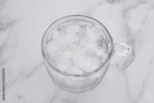 drinking enough water or sobriety concept, pint glass with tap water and ice cubes over marble background