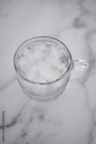 drinking enough water or sobriety concept, pint glass with tap water and ice cubes over marble background