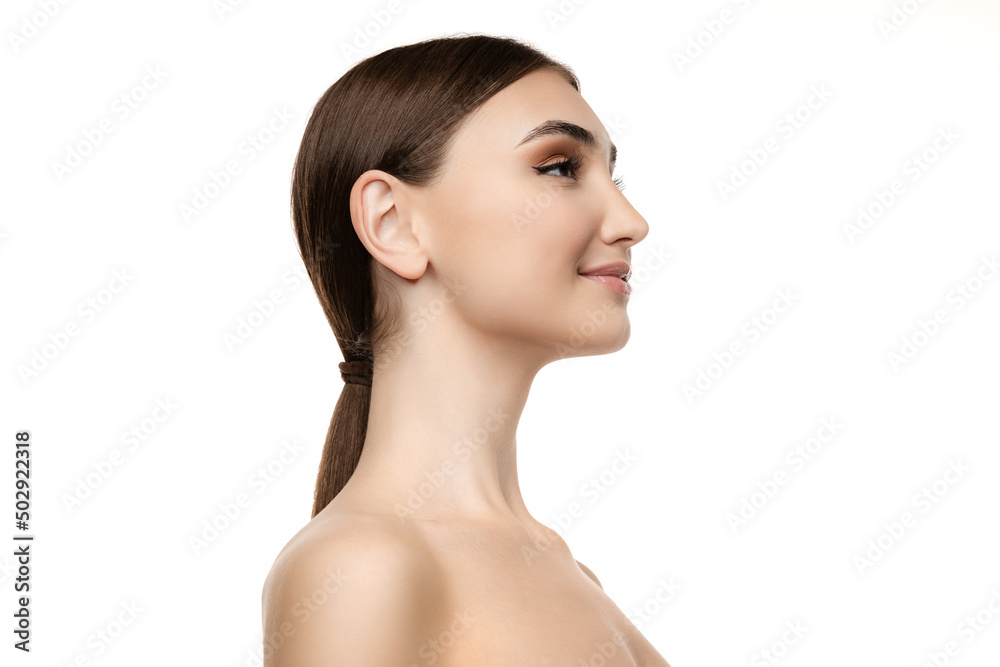 Side view portrait of young beautiful woman with low ponytail posing isolated over white studio background. Natural look Side view portrait of young beautiful woman with low ponytail posing isolated over white studio background. Natural look