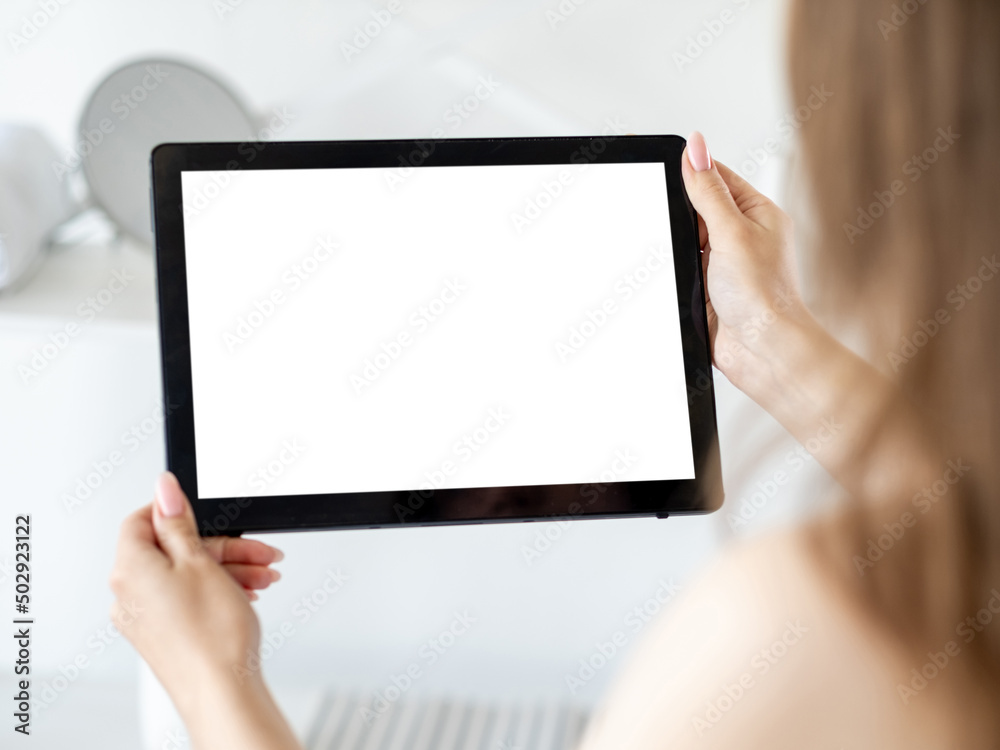 Mobile news. Digital mockup. Virtual connection. Unrecognizable woman holding tablet computer with blank screen in light home interior blur.
