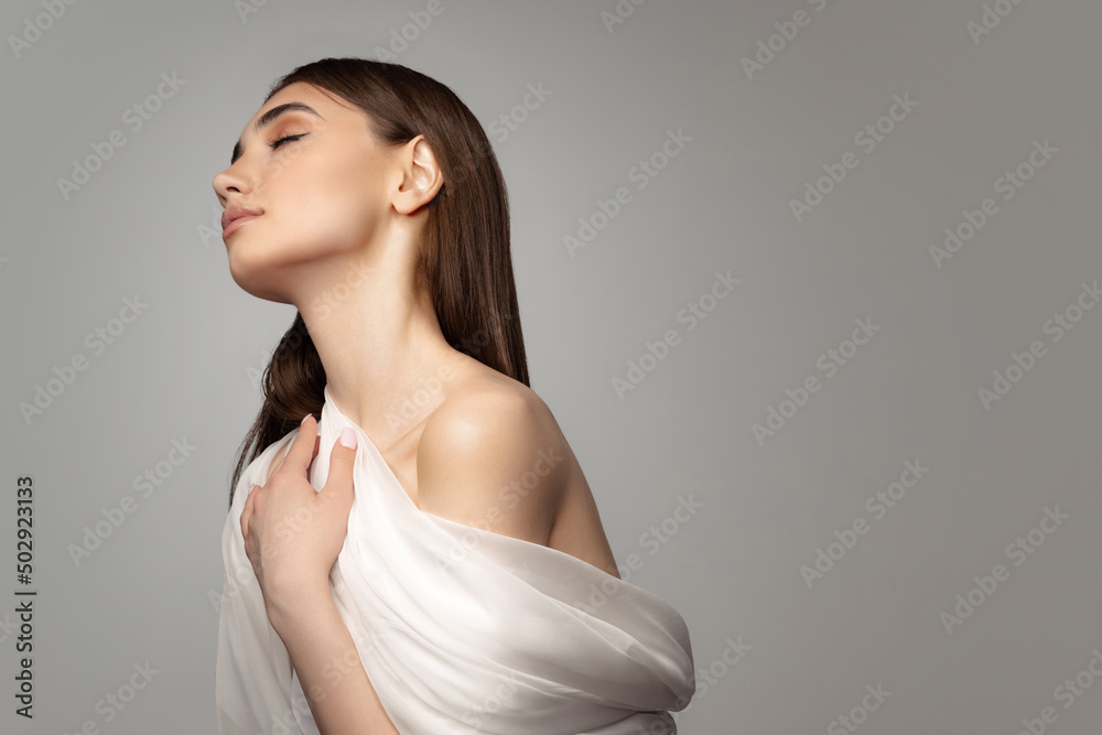 Portrait of tender young woman covered with white veil isolated over grey background. Sensuality Portrait of tender young woman covered with white veil isolated over grey background. Sensuality