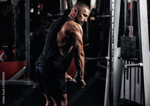 Handsome fitness man working out in the gym. Arms biceps and triceps workout