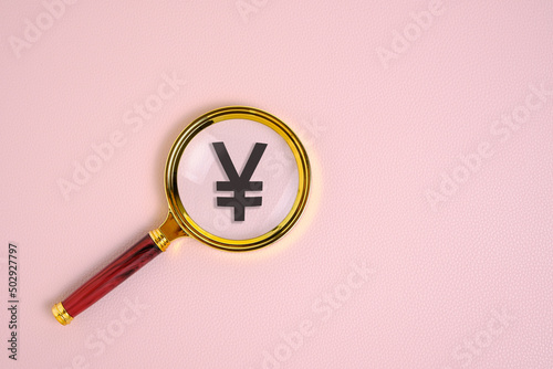 Yuan symbol under magnifying glass, on pink background.