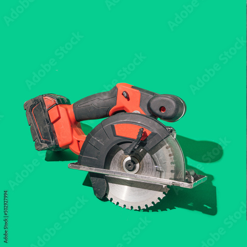 A brushless cordless circular saw on beautiful green background with sunny shadow